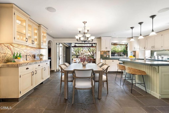 dining space featuring arched walkways, stone tile flooring, recessed lighting, and an inviting chandelier