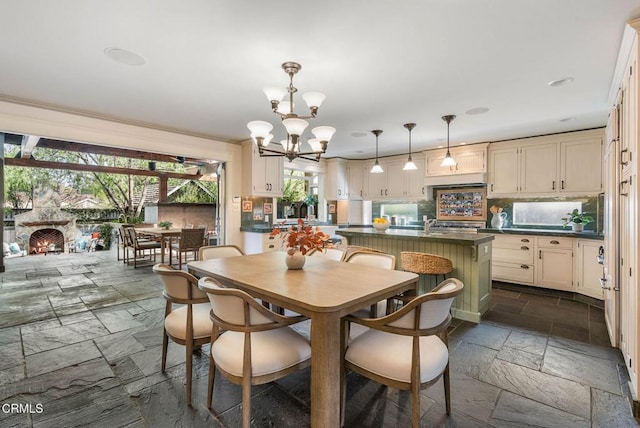 dining room with a notable chandelier, a stone fireplace, and stone tile floors