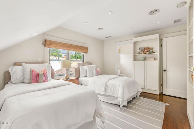 bedroom featuring lofted ceiling, visible vents, and dark wood finished floors