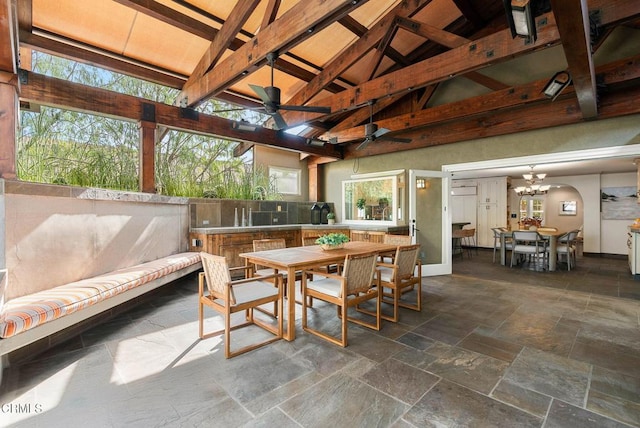 sunroom featuring vaulted ceiling with beams, arched walkways, and ceiling fan with notable chandelier