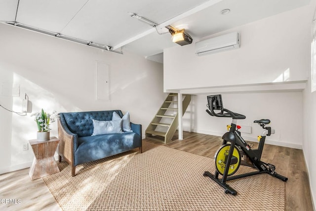 exercise room with a garage, electric panel, baseboards, wood finished floors, and a wall mounted AC