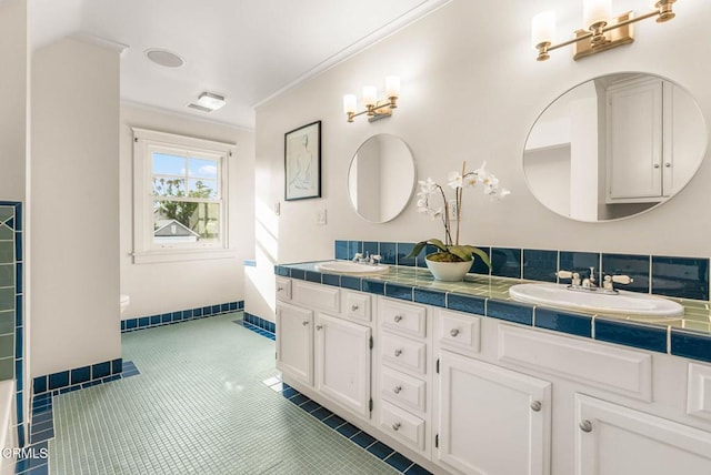 bathroom with double vanity, tile patterned flooring, a sink, and crown molding