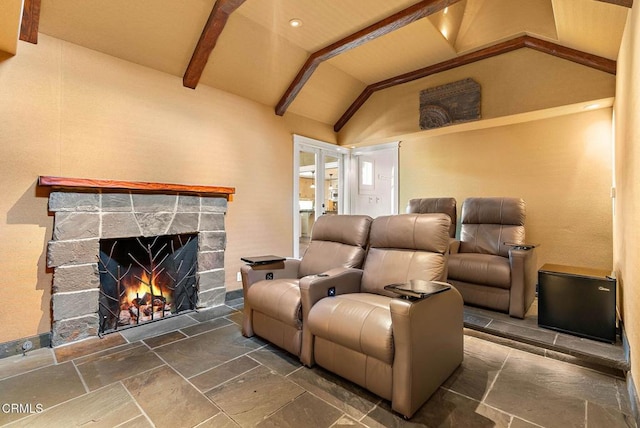 home theater with lofted ceiling with beams, a stone fireplace, and stone tile floors