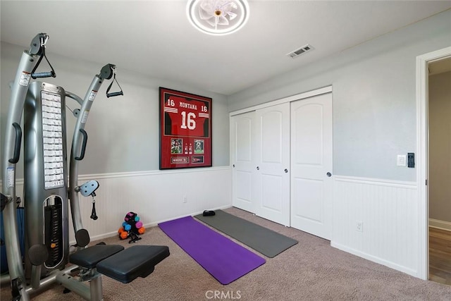 workout room featuring carpet floors, visible vents, and wainscoting