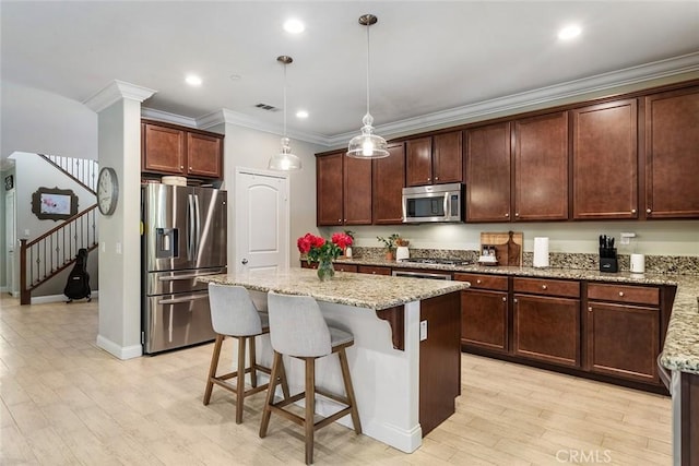 kitchen with a center island, crown molding, stainless steel appliances, visible vents, and light wood-style flooring