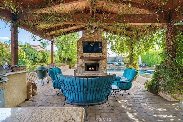 view of patio / terrace with a swimming pool, area for grilling, and an outdoor living space with a fireplace