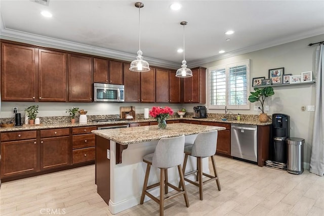 kitchen with light stone counters, a breakfast bar area, stainless steel appliances, light wood-style floors, and ornamental molding