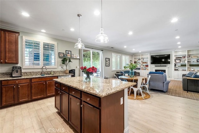 kitchen featuring light stone countertops, a fireplace, ornamental molding, and a sink