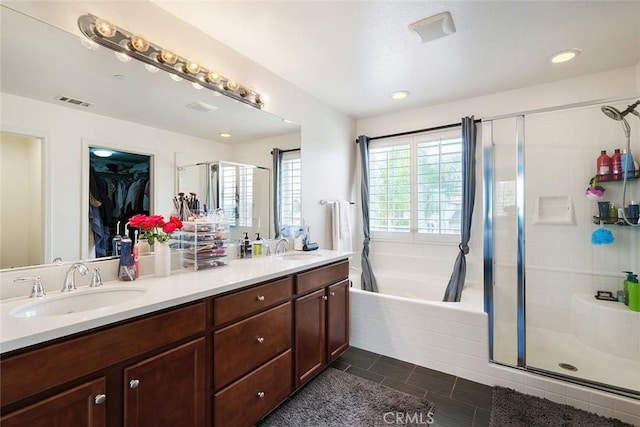 bathroom with a stall shower, double vanity, a sink, and a bath