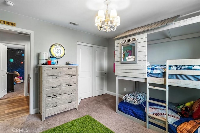 carpeted bedroom with baseboards, a closet, visible vents, and an inviting chandelier