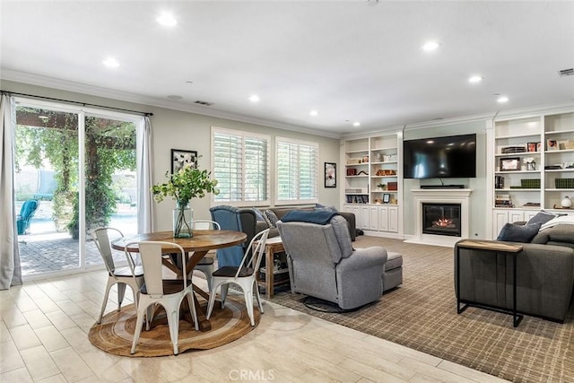 living area with visible vents, a glass covered fireplace, wood finished floors, crown molding, and recessed lighting