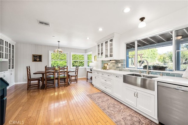 kitchen with a sink, light wood-style floors, light countertops, and stainless steel dishwasher