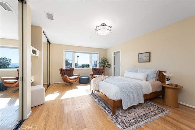 bedroom with light wood-style flooring, visible vents, and baseboards