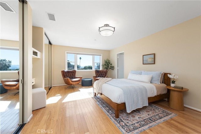 bedroom with baseboards, light wood-style floors, and visible vents