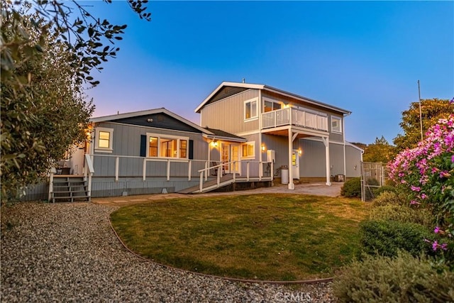 back of property with a balcony, fence, a lawn, and a patio