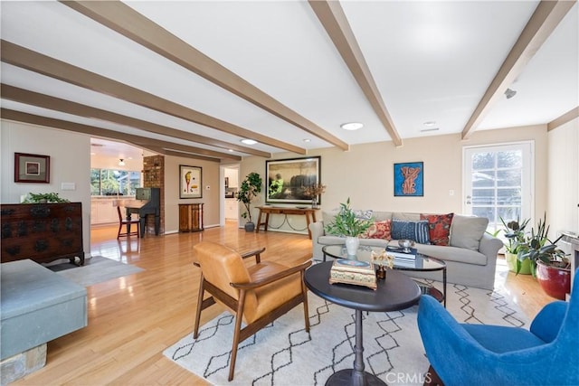 living area featuring light wood finished floors and beamed ceiling