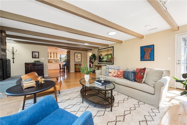 living room with a fireplace, beamed ceiling, and wood finished floors