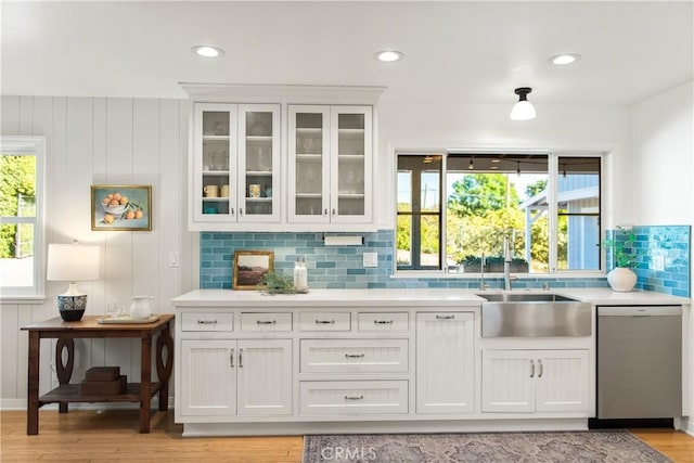 bar featuring a sink, a healthy amount of sunlight, decorative backsplash, and dishwasher