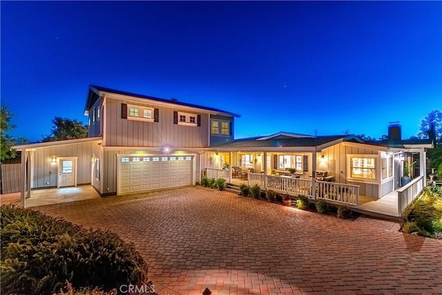 back of house at night featuring decorative driveway