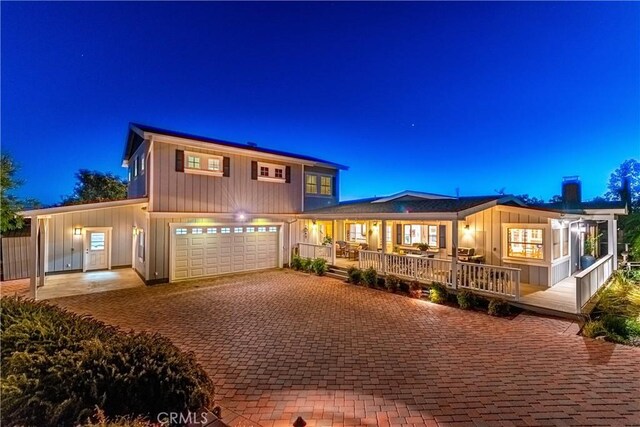 view of front of house with board and batten siding, decorative driveway, an attached garage, and a chimney