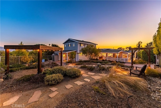 back of house at dusk featuring a garage, fence, and board and batten siding