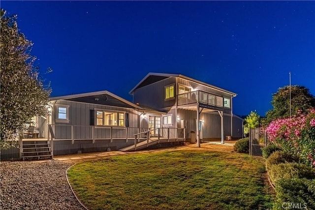 back of house at twilight featuring fence and a balcony