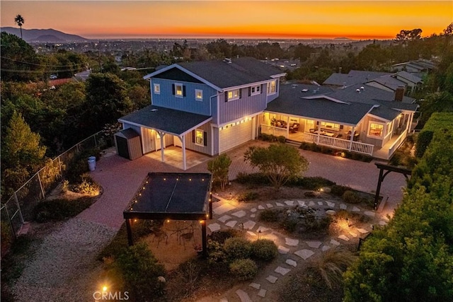 back of house at dusk featuring a garage and fence