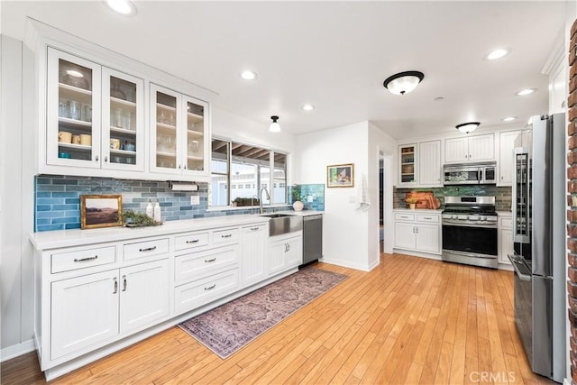 kitchen with white cabinets, appliances with stainless steel finishes, light countertops, and a sink