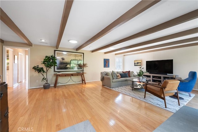 living room featuring beamed ceiling, wood-type flooring, and baseboards