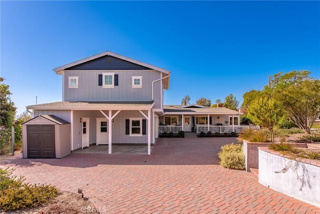 rear view of property featuring covered porch, an outdoor structure, and a storage shed