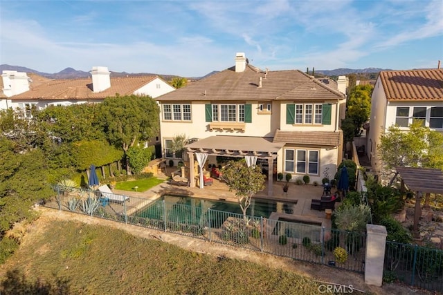 rear view of house featuring a patio area, a fenced backyard, a tile roof, and stucco siding