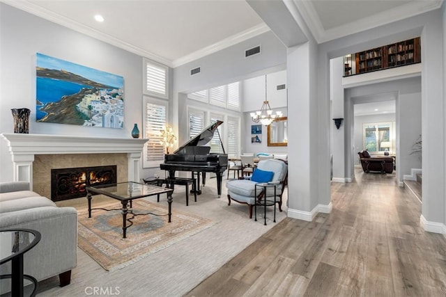 sitting room with crown molding, visible vents, wood finished floors, a warm lit fireplace, and baseboards