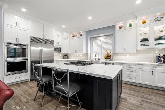 kitchen with built in appliances, a sink, and white cabinetry