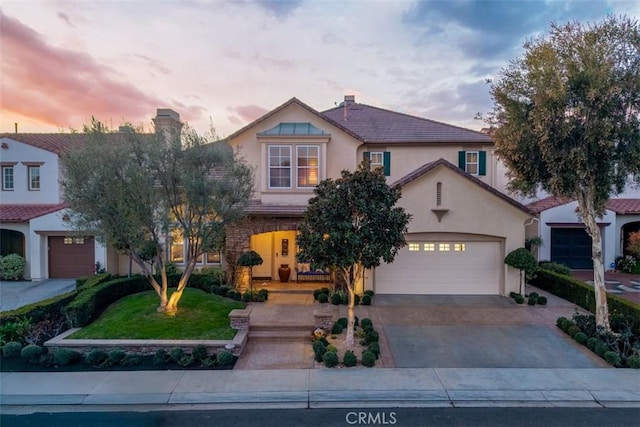 view of front of home featuring a garage, driveway, a tiled roof, stucco siding, and a chimney