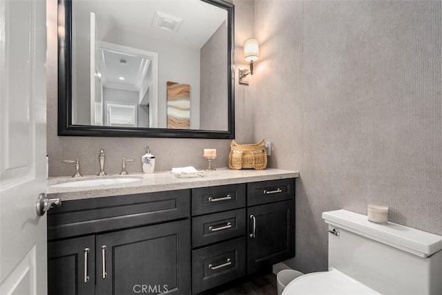 half bathroom featuring toilet, visible vents, and vanity