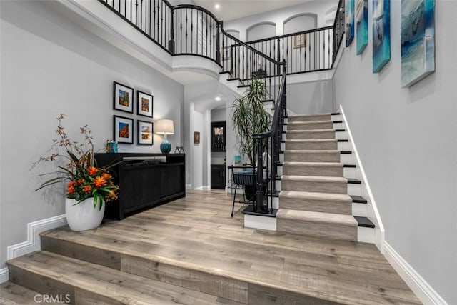 foyer entrance featuring stairs, a high ceiling, wood finished floors, and baseboards