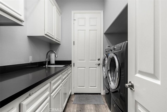 laundry area featuring wood finished floors, a sink, cabinet space, and washer and dryer