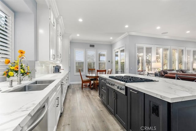 kitchen with dark cabinets, white cabinets, a sink, and appliances with stainless steel finishes