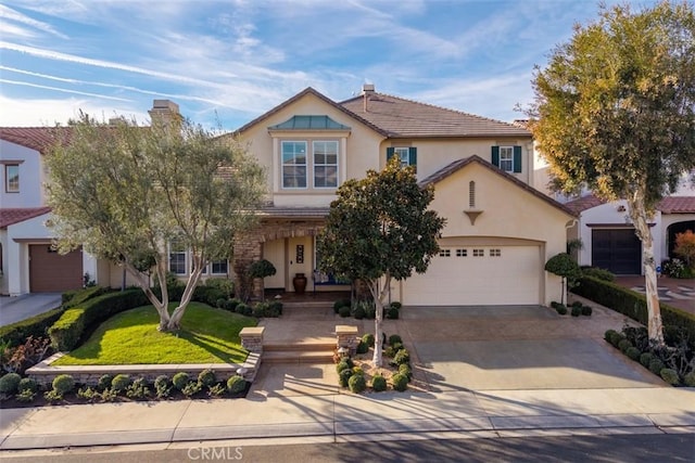 view of front facade featuring an attached garage, concrete driveway, a tiled roof, stucco siding, and a front yard