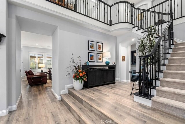 foyer featuring a towering ceiling, stairway, baseboards, and wood finished floors