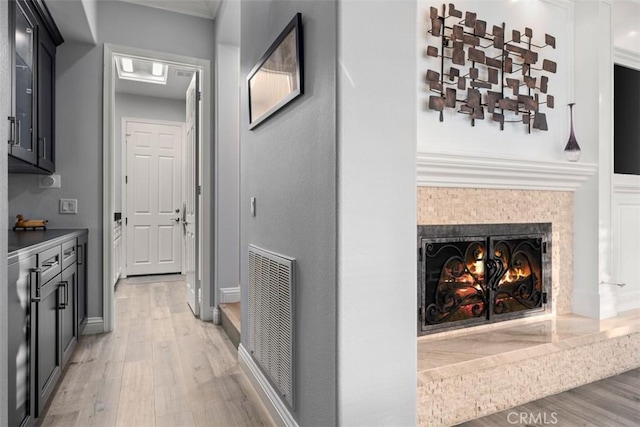 hallway featuring light wood finished floors, baseboards, and visible vents