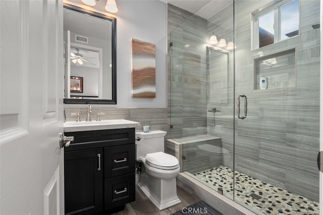 full bath with toilet, a shower stall, visible vents, and tile walls