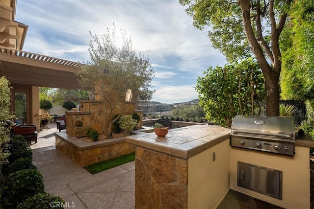 view of patio / terrace with exterior kitchen, a grill, and fence