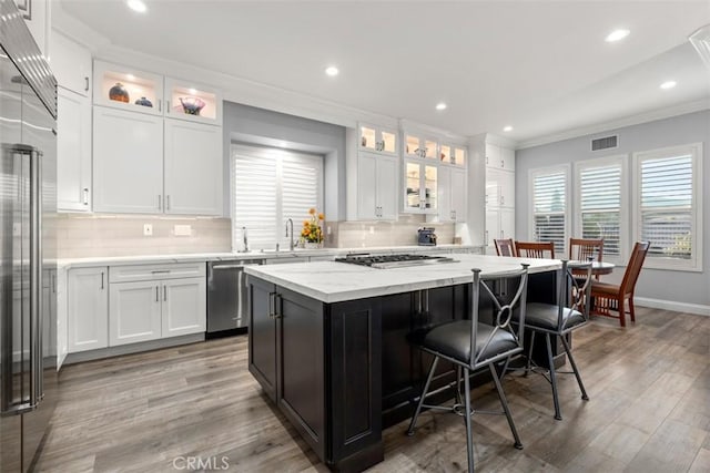 kitchen featuring visible vents, white cabinets, appliances with stainless steel finishes, a breakfast bar area, and a center island