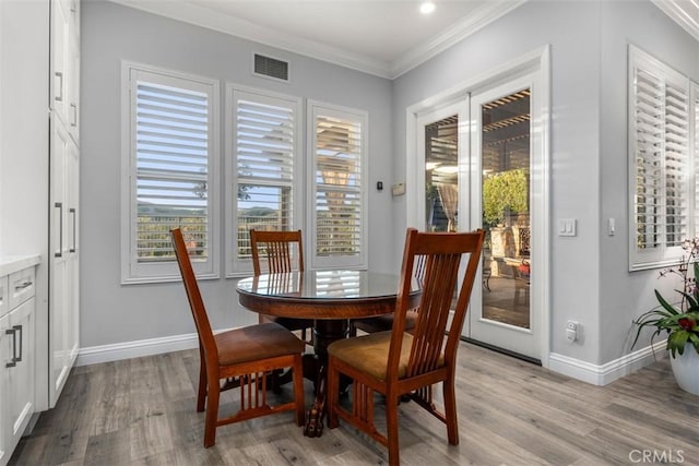 dining room with light wood-style floors, visible vents, crown molding, and baseboards