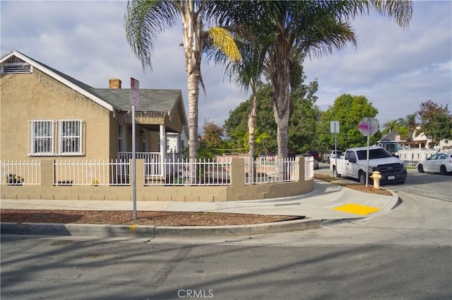 view of front facade featuring a fenced front yard, roof with shingles, and stucco siding