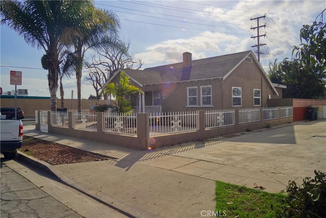 view of front of house featuring a fenced front yard, a chimney, and stucco siding