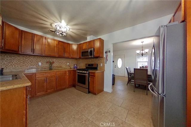 kitchen featuring a chandelier, stainless steel appliances, light countertops, decorative backsplash, and brown cabinetry