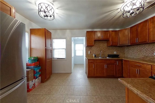 kitchen with light countertops, brown cabinetry, backsplash, and freestanding refrigerator