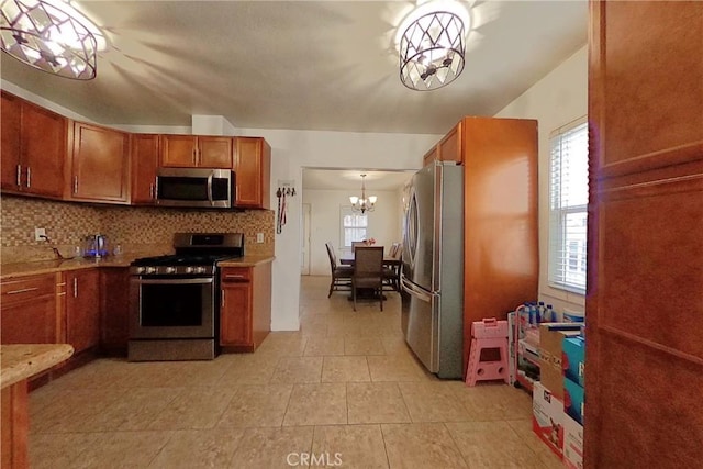 kitchen featuring decorative backsplash, brown cabinetry, appliances with stainless steel finishes, an inviting chandelier, and light countertops